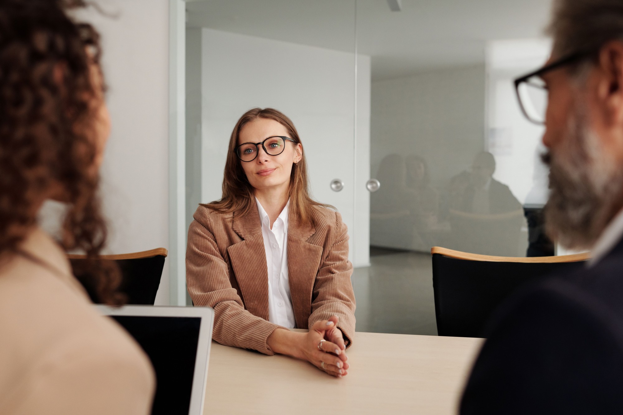 A job applicant wearing glasses sits across from hiring managers during a marketing interview